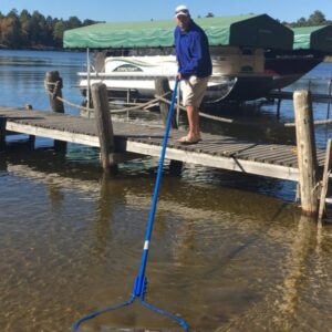Individual using rake at lakeside dock